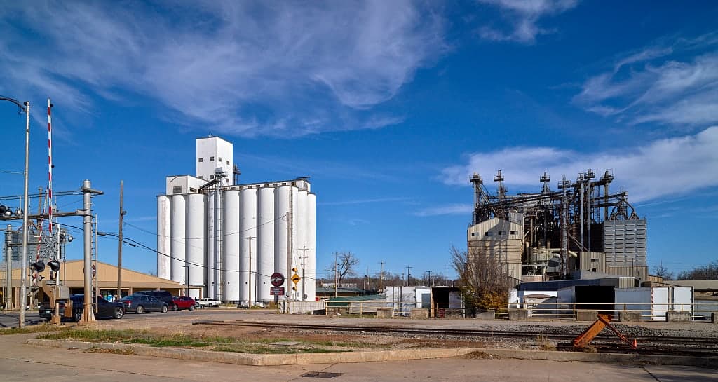 A grain elevator on the edge of Stillwater, Oklahoma, standing beside the rail crossing