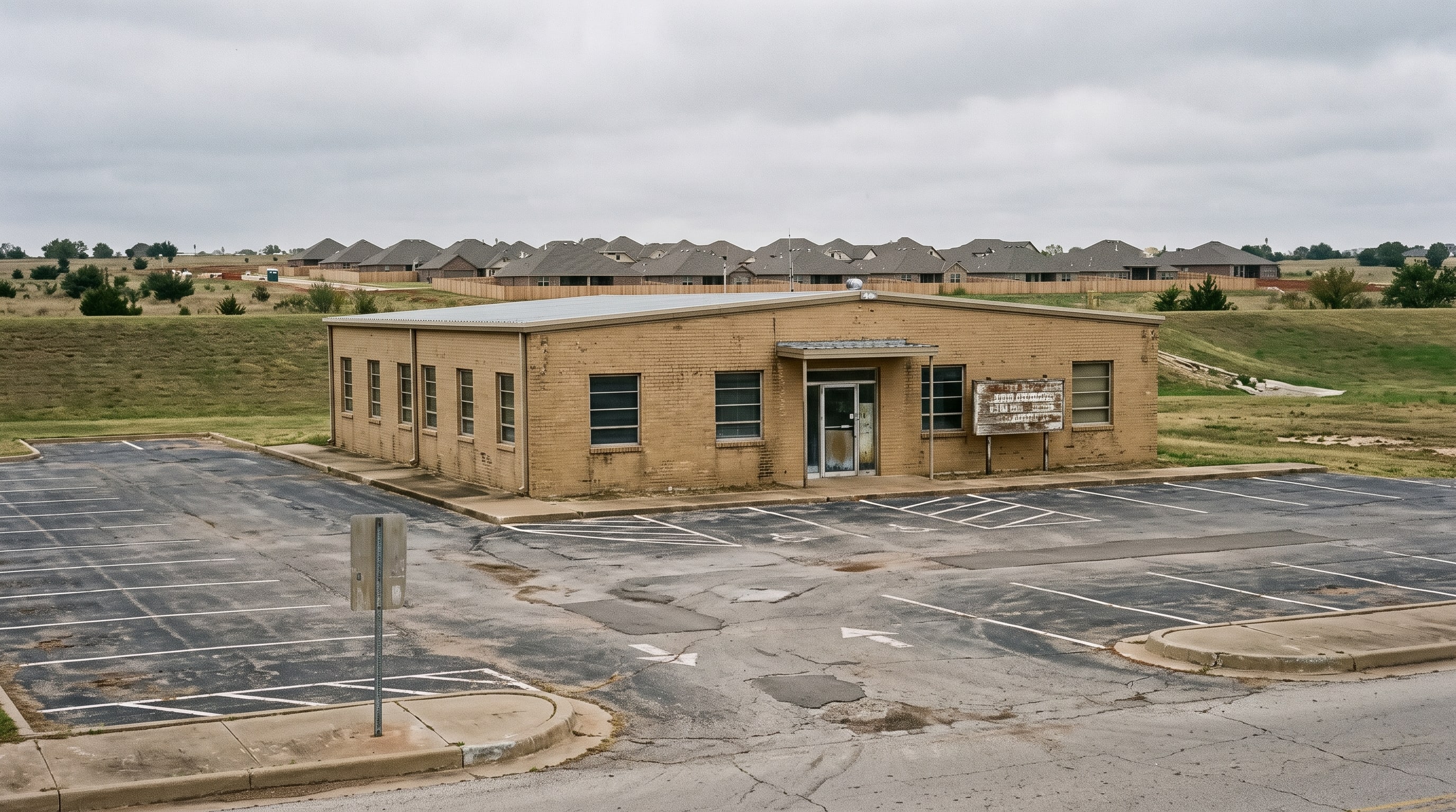 A low tan-brick county administration building beside a full parking lot, new rooftops behind.